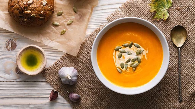 pumpkin soup with bread on background